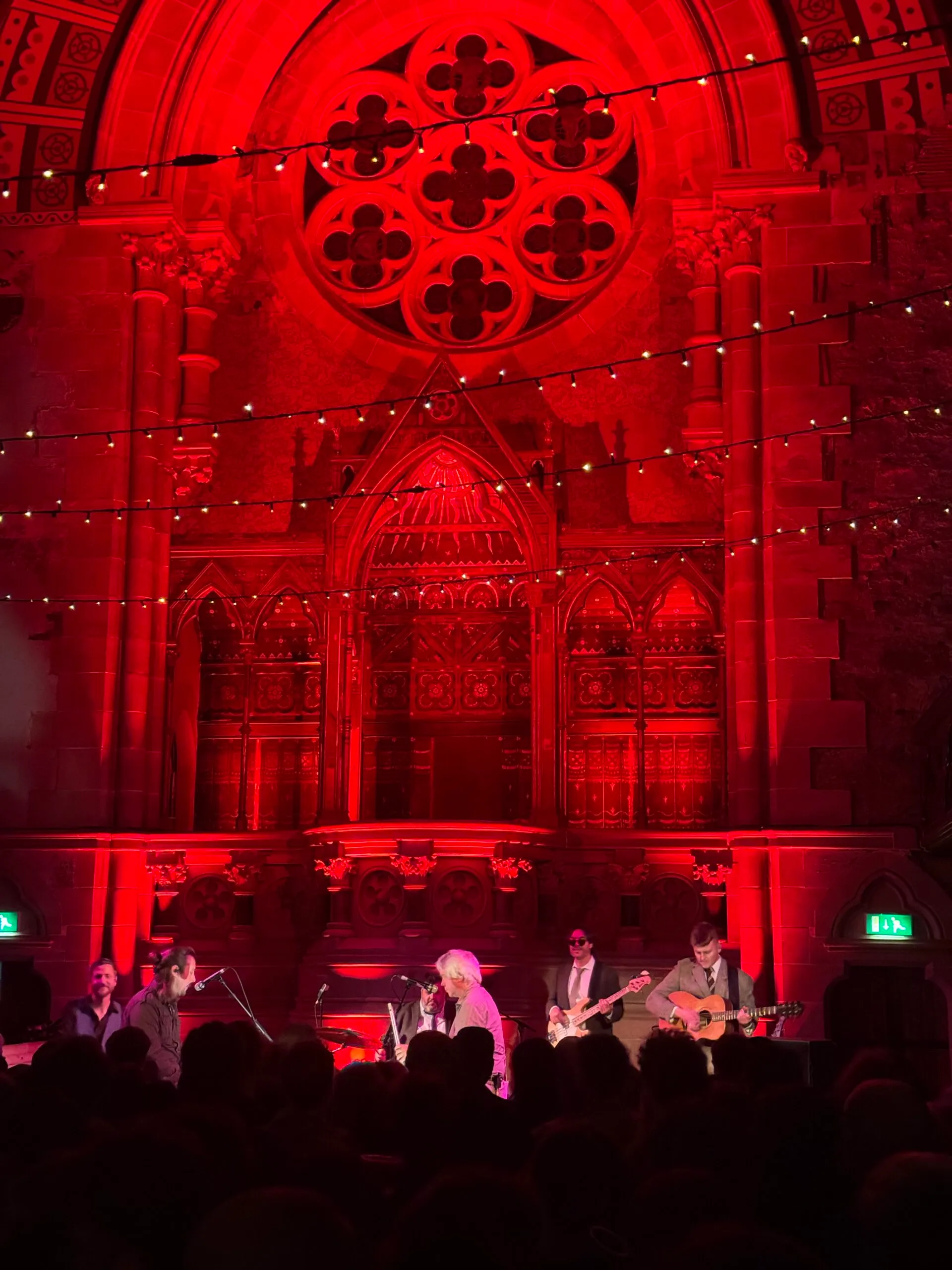 A group of musicians playing in a red-lit church setting